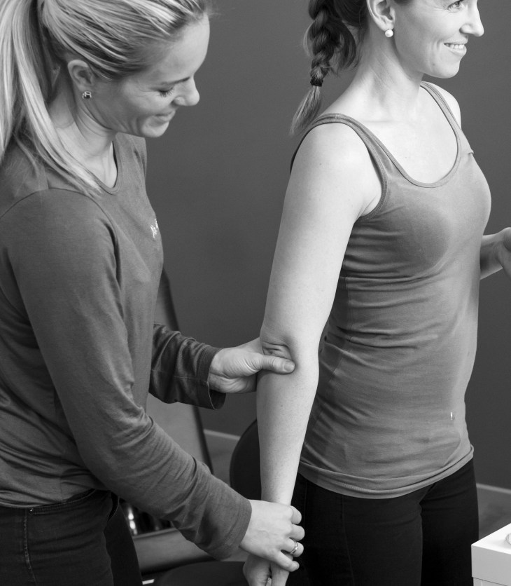 Kiropraktor justere og undersøker albue og skulder på pasient