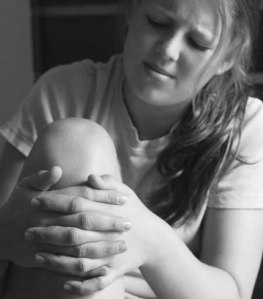 Ung jente med smerter i kneet. Holder seg på kneet med hendene